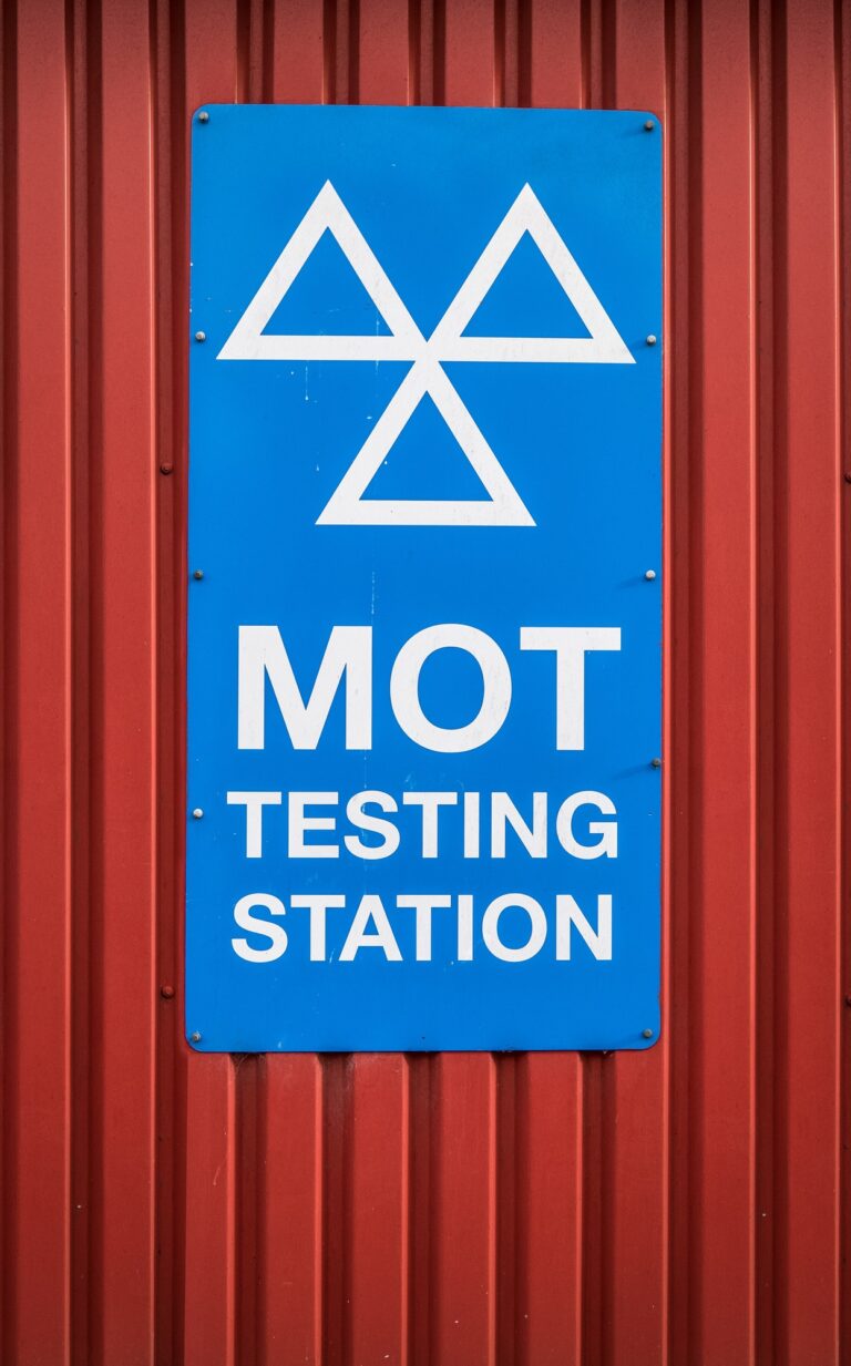 MOT testing station sign featuring the DVSA logo and clear text indicating "MOT TESTING STATION," set against a red corrugated background, relevant to vehicle services in Sittingbourne.
